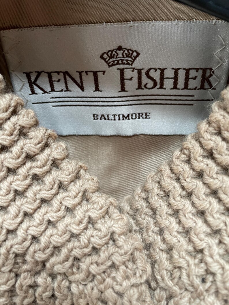 May include: A white label with brown text that reads "Kent Fisher Baltimore" and a crown logo above the text.