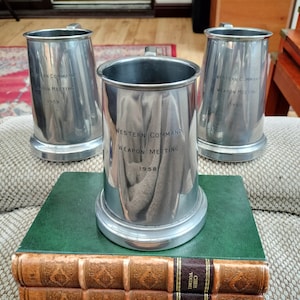 May include: Three silver metal mugs with the inscription "Western Command Weapon Meeting" and the years 1955, 1958, and 1960.