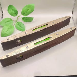 May include: Two vintage spirit levels with dark wood bodies and brass edges. Each level has a green bubble vial and is marked "J.A. Marston & Sons, Birmingham, Made in England."