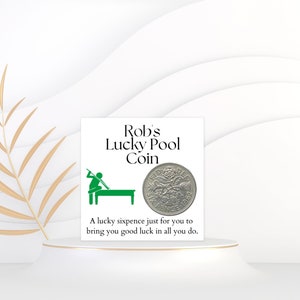 May include: A white card with green text that reads "Rob's Lucky Pool Coin". A green illustration of a person playing pool is on the left side of the card. A silver sixpence coin is on the right side of the card. The text below the coin reads "A lucky sixpence just for you to bring you good luck in all you do."