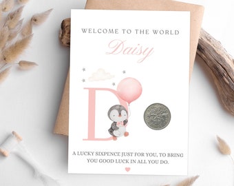 May include: A white card with pink accents and a penguin illustration. The card says "Welcome to the world Daisy" and "A lucky sixpence just for you, to bring you good luck in all you do."