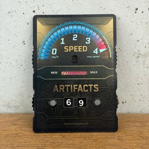 May include: A black Artifacts card with a speedometer design. The speedometer reads 0 mph/h to 4 max speed. The card also displays the numbers 69 and the text "ARTIFACTS". The website address www.tokenx.at is at the bottom.