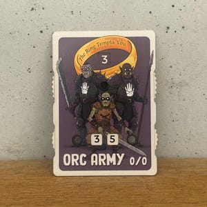 Puede incluir: Carta coleccionable con tres orcos armados sobre un fondo púrpura. El texto "The Ring Tempts You" y "ORC ARMY 0/0" es visible. La carta también muestra los números 3, 3 y 5.