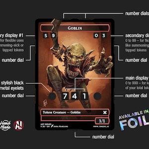 May include: A fantasy-themed card featuring a goblin illustration with a menacing expression. The card has multiple number dials and displays for tracking game stats. The card is labeled "Goblin" and "Token Creature".