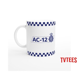 Op de afbeelding: Witte keramische mok met een blauw-wit geblokt patroon aan de boven- en onderkant. De mok heeft de tekst "AC-12" in blauw, samen met een politielogo.