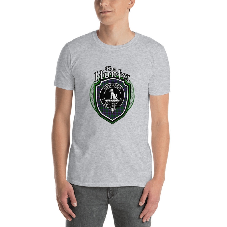 May include: A heather grey t-shirt with a black and green clan crest featuring a dog and the text "Clan Hunter" in a black banner.
