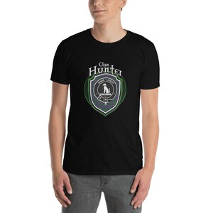 May include: Black t-shirt with a green, white, and purple clan crest featuring a dog and the text "Clan Hunter - Crest o' Hunter".