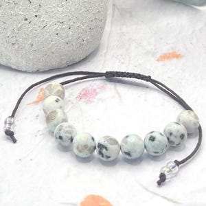 a Beautiful 10 Breaths Bracelet, featuring 10, 8mm stones that are a creamy light green speckled with dark and clear marks.  These stones are not highly polished, they are half matte, which add to their beauty.
