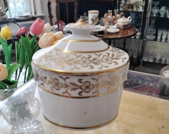 May include: White porcelain sugar bowl with a gold lid and floral design. The bowl has a gold trim around the top and bottom.