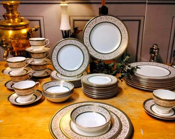 May include: A set of white china dinnerware with gold trim and floral patterns. The set includes dinner plates, salad plates, bowls, and teacups and saucers.