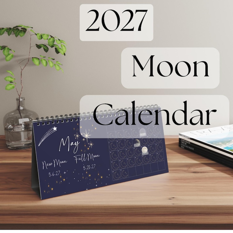 May include: A 2027 Moon Calendar desk calendar with a dark blue background featuring white text and celestial illustrations. The page displays the month of May, noting the New Moon on 5-6-27 and Full Moon on 5-20-27, alongside a grid of moon phases.