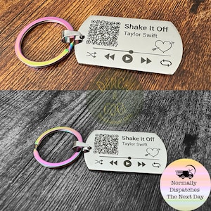 May include: Silver keychain with a QR code, play button, and the text "Shake It Off Taylor Swift".