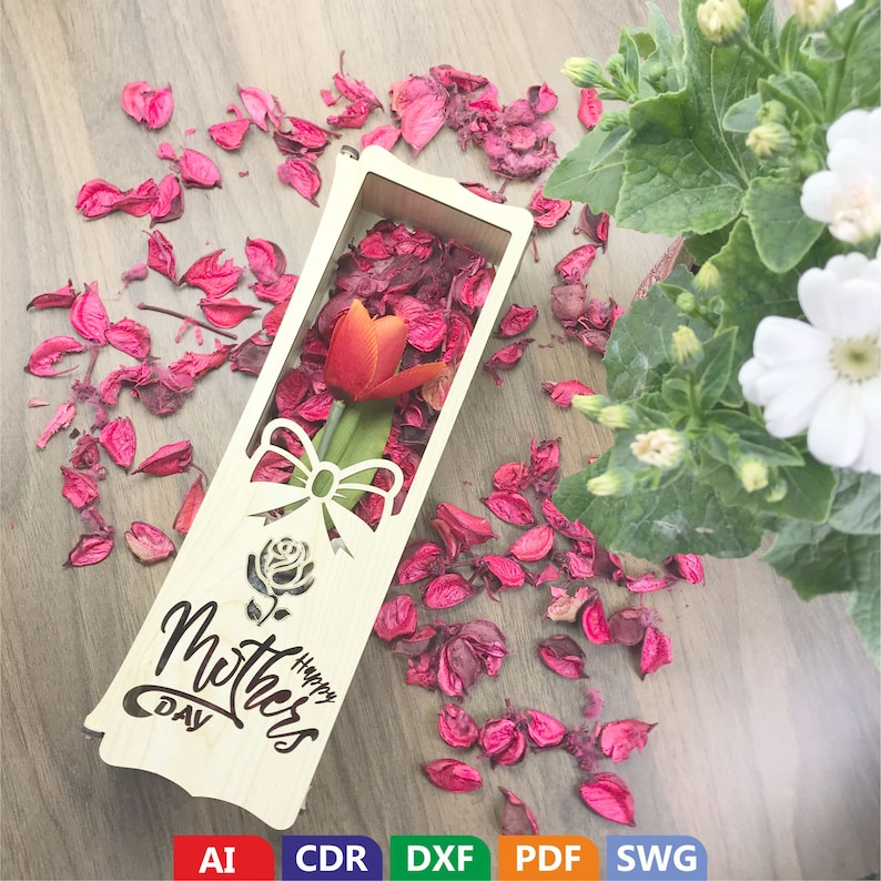 May include: A wooden box with a cutout design of a rose and a bow. The box is decorated with the words "Happy Mother's Day". A single red tulip is placed inside the box, surrounded by pink flower petals.