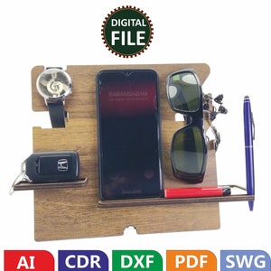May include: A wooden organizer with slots for a phone, watch, keys, sunglasses, and a pen. The organizer is brown and has a natural wood finish. The phone slot has a phone in it with the text "BABAMBABAM" on the screen. The watch slot has a watch with a musical note design on the face. The key slot has a car key with a Honda logo. The sunglasses slot has a pair of sunglasses. The pen slot has a blue pen.