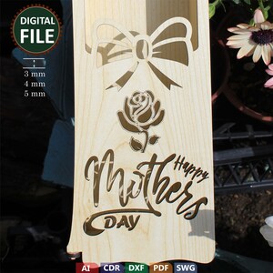 May include: A wooden cutout of a rose and a bow with the text "Happy Mothers Day" on a light brown background. The cutout is designed for laser cutting.