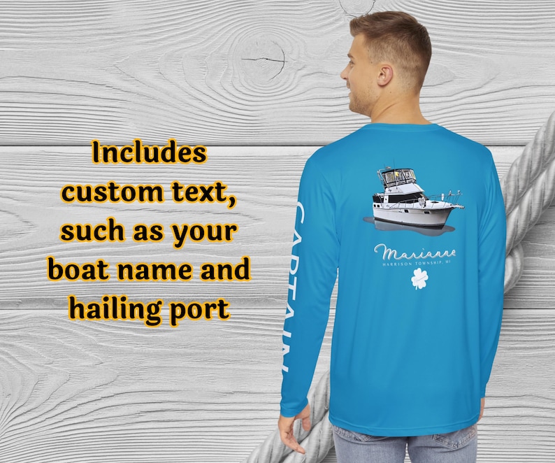 May include: A light blue long-sleeve shirt with a boat graphic on the back. The shirt includes the text "CAPTAIN" on the left sleeve and the text "Includes custom text, such as your boat name and hailing port" on the left side.