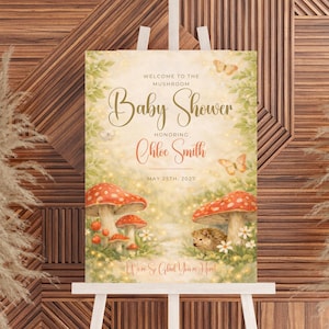 Może przedstawiać: Znak baby shower na sztaludze z fantazyjnym motywem grzybów. Na znaku widnieje napis "Witamy na Baby Shower Grzybów ku czci Chloe Smith, 25 maja 2027 r.". Ilustracja zawiera grzyby, motyle i jeża.