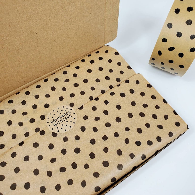 May include: A brown cardboard box with a brown and black polka dot patterned tissue paper inside. The tissue paper has a round sticker that says "Handmade with Love".