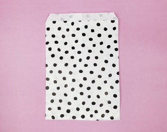 May include: A white paper bag with a black polka dot pattern. The bag is folded and ready to be used.