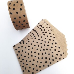 May include: A roll of brown paper tape with black polka dots and a stack of brown paper envelopes with black polka dots.