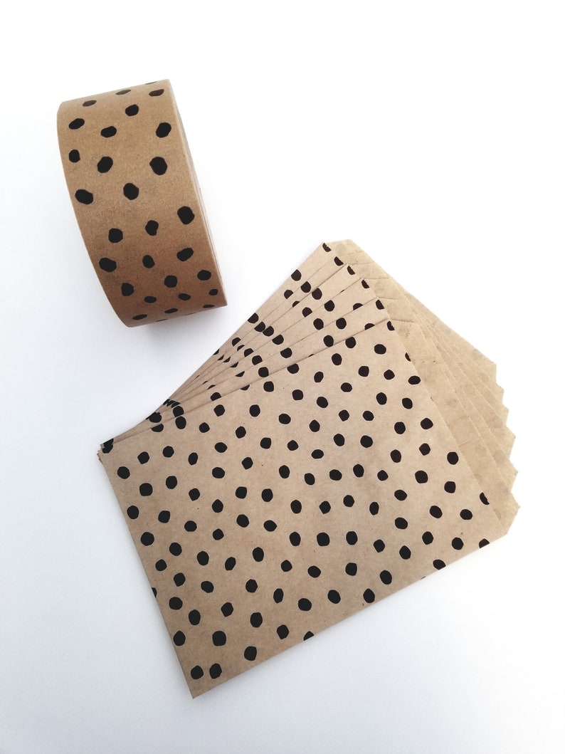 May include: A roll of brown paper tape with black polka dots and a stack of brown paper envelopes with black polka dots.