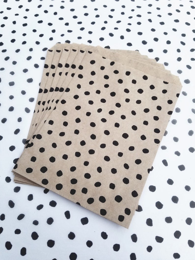 May include: A stack of brown paper bags with a black polka dot pattern. The bags are folded and stacked on top of each other.