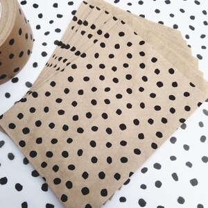 May include: A stack of brown paper envelopes with a black polka dot pattern. The envelopes are on a white background with a black polka dot pattern.