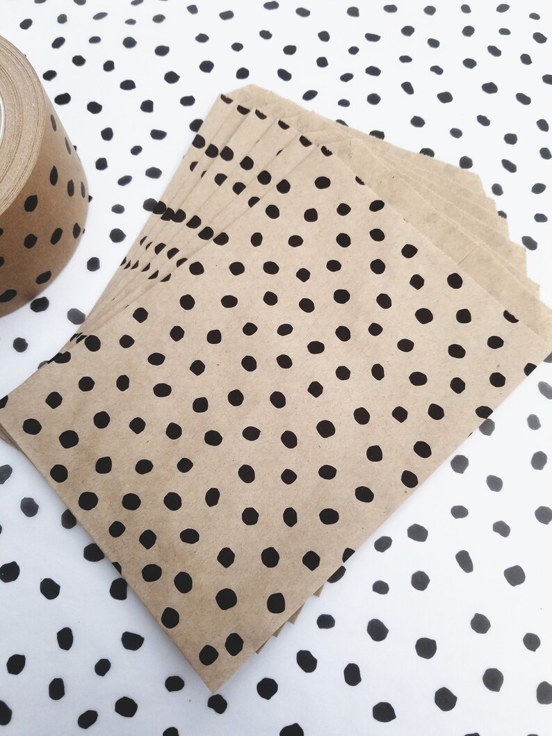 May include: A stack of brown paper envelopes with a black polka dot pattern. The envelopes are on a white background with a black polka dot pattern.