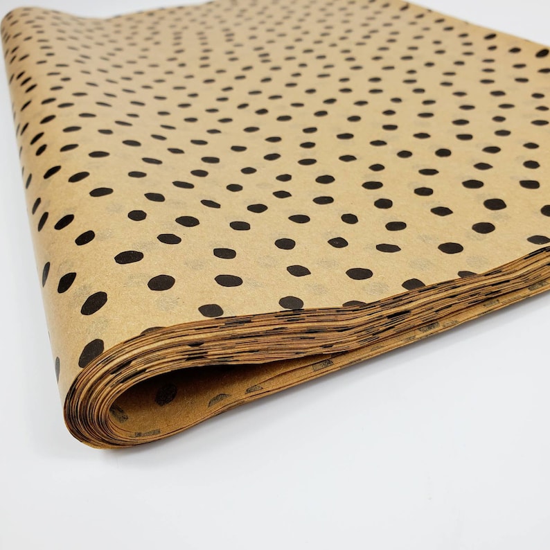 May include: A roll of brown wrapping paper with a black polka dot pattern. The paper is folded and stacked.