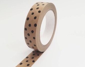Puede incluir: Un rollo de cinta washi marrón con lunares negros. La cinta está parcialmente desenrollada, mostrando el patrón.