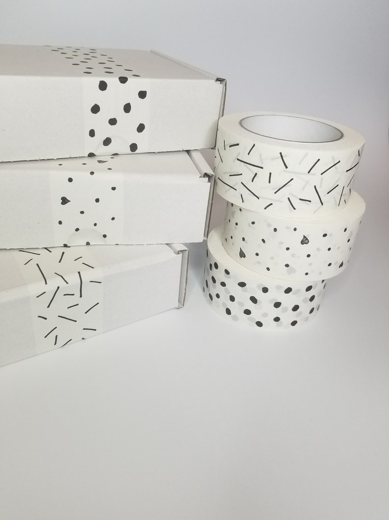 May include: Four rolls of white washi tape with black and white geometric patterns. The patterns include dots, lines, and a combination of dots and lines.