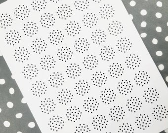 May include: A white sheet of paper with a pattern of black polka dots arranged in circles. The circles are of varying sizes and are arranged in a staggered pattern.