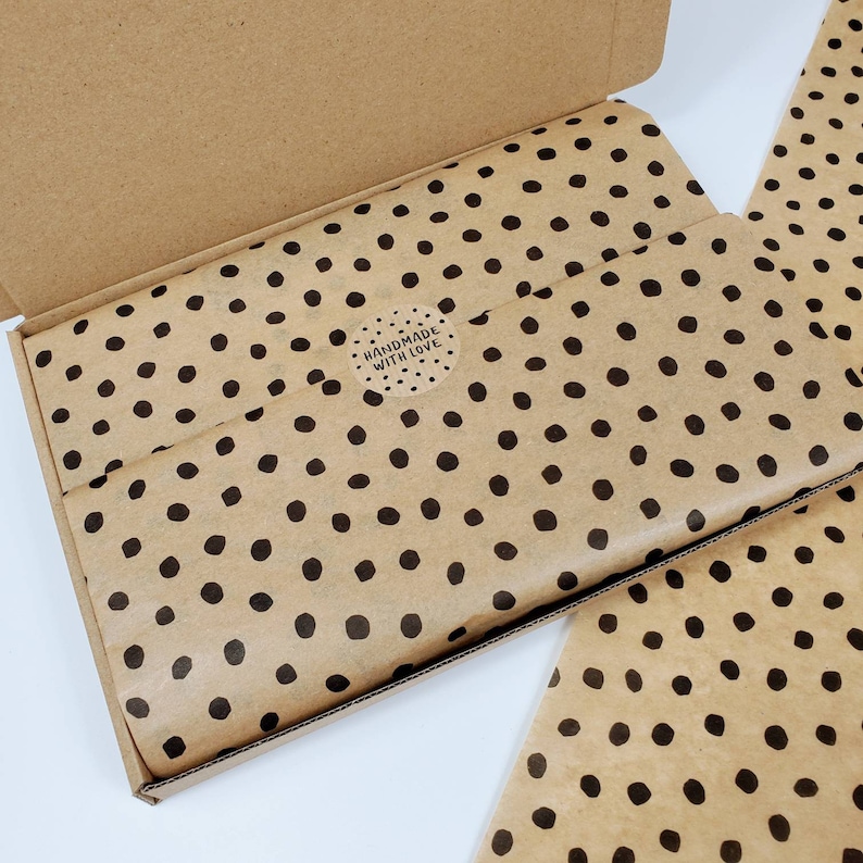 May include: A brown cardboard box with a lid open, revealing brown tissue paper with black polka dots. The tissue paper has a round sticker that says "Handmade with Love".