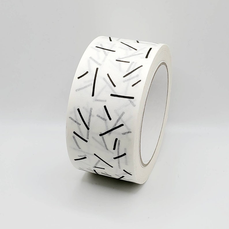 May include: A roll of white packing tape with a black and white geometric pattern. The tape has a repeating pattern of thin black lines.
