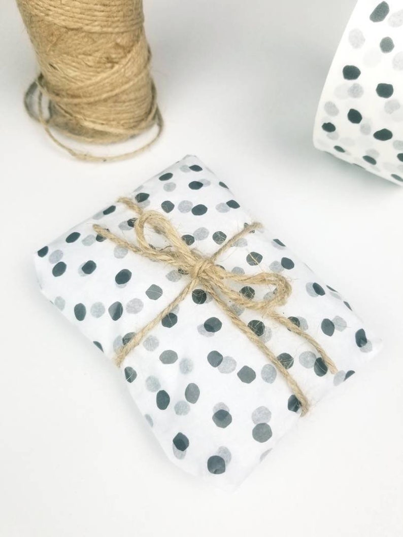 May include: A small gift wrapped in white paper with black polka dots. The gift is tied with twine and a bow.