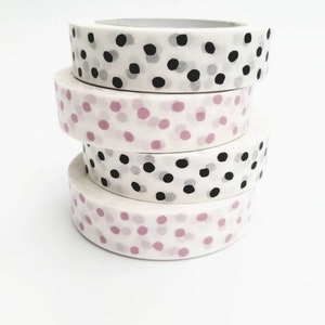 May include: Four rolls of washi tape with different polka dot patterns. The top roll has black and gray polka dots on a white background. The second roll has pink polka dots on a white background. The third roll has black and gray polka dots on a white background. The bottom roll has pink polka dots on a white background.