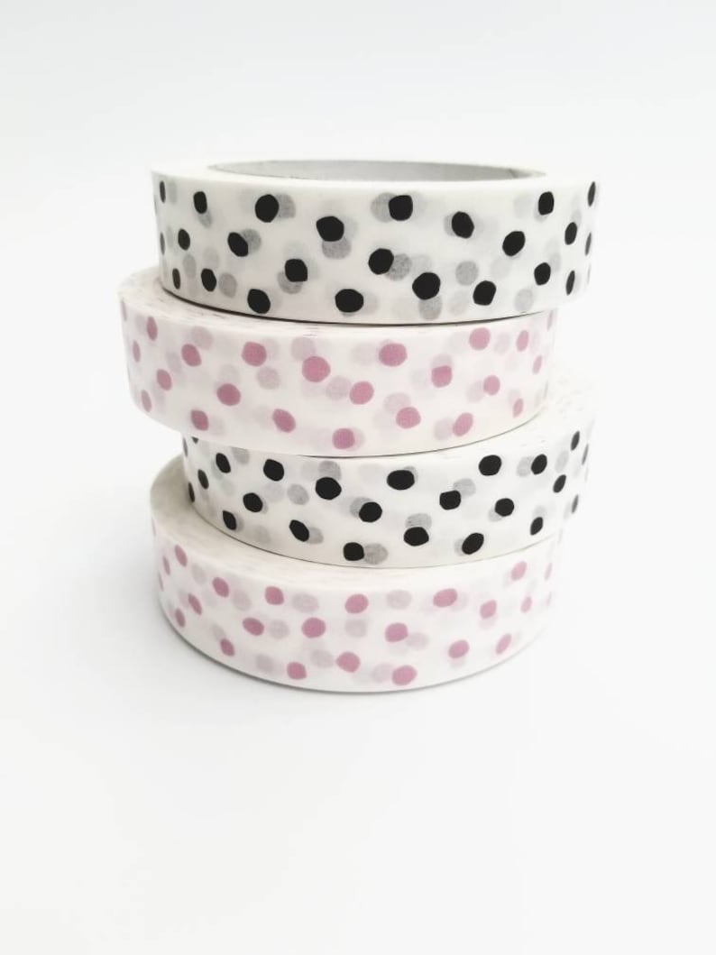May include: Four rolls of washi tape with different polka dot patterns. The top roll has black and gray polka dots on a white background. The second roll has pink polka dots on a white background. The third roll has black and gray polka dots on a white background. The bottom roll has pink polka dots on a white background.