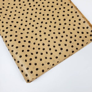 May include: Brown wrapping paper with a repeating pattern of black polka dots.