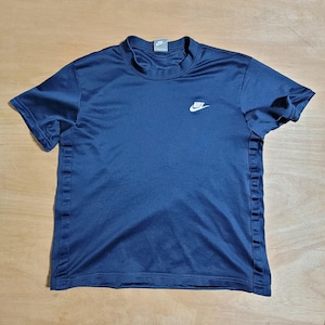 Puede incluir: Una camiseta azul marino de manga corta con un logotipo blanco de Nike en la parte delantera.