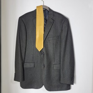 May include: A dark gray blazer with a yellow tie. The blazer has a button closure and two pockets.