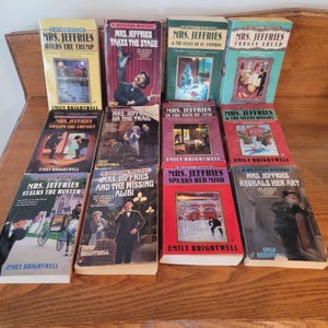 May include: A collection of vintage mystery novels by Emily Brightwell, featuring the character Mrs. Jeffries. The books have colorful covers with illustrations and titles like "Mrs. Jeffries Holds the Trump" and "Mrs. Jeffries Takes the Stage."