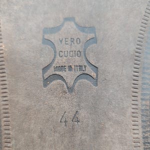 May include: Close-up of a shoe sole with the embossed text "VERO CUOIO MADE IN ITALY". The number "44" is also visible. The sole is dark gray and has a textured surface.