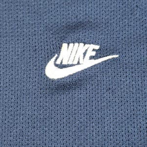 Puede incluir: Un logotipo blanco de Nike sobre una tela azul marino con un patr&oacute;n texturizado.