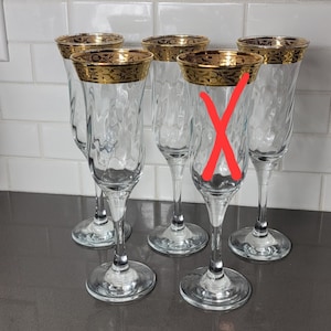Op de afbeelding: Set van vijf champagnefluiten met gouden randen. De fluiten zijn van helder glas en hebben een delicaat ontwerp.