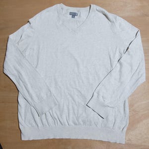 May include: A light beige long-sleeved v-neck sweater.