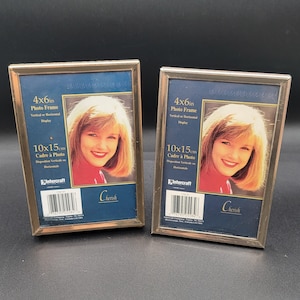 May include: Two rectangular photo frames with a gold-colored metal finish. Each frame holds a photo of a woman with blonde hair. The frames are labeled "4x6in Photo Frame" and "10x15cm Cadre à Photo". The word "Cherish" is printed on the bottom.