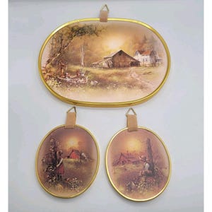 May include: A set of three oval wall plaques with gold-toned metal frames. The large top plaque depicts a rural farm scene with a barn and a well. The two smaller bottom plaques feature illustrations of children in a field with barns in the background.
