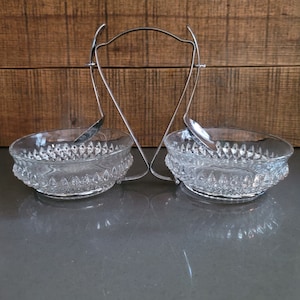 May include: A set of two clear glass bowls with a diamond pattern, attached to a silver metal stand with two spoons.