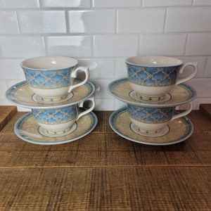 May include: Four teacups and saucers with a blue and gold floral pattern. The cups and saucers are stacked in pairs.