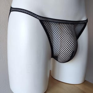 Può includere: Intimo in rete nera con taglio a vita bassa e una fascia larga.